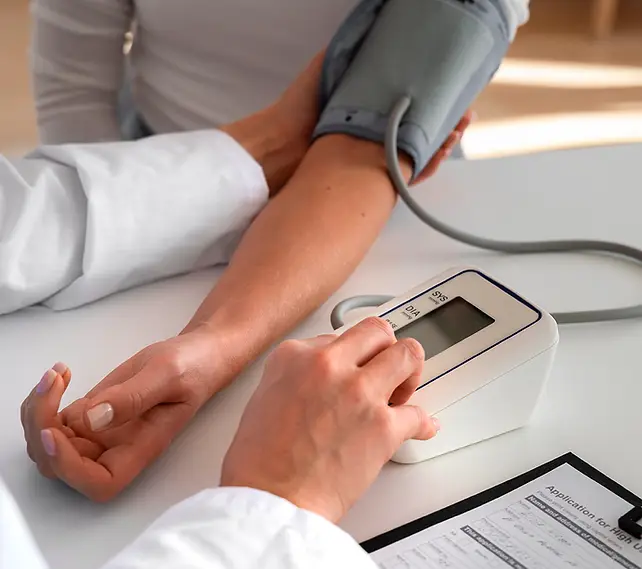 Healthcare professional taking a patient's blood pressure using an electronic monitor during a biometric screening.
