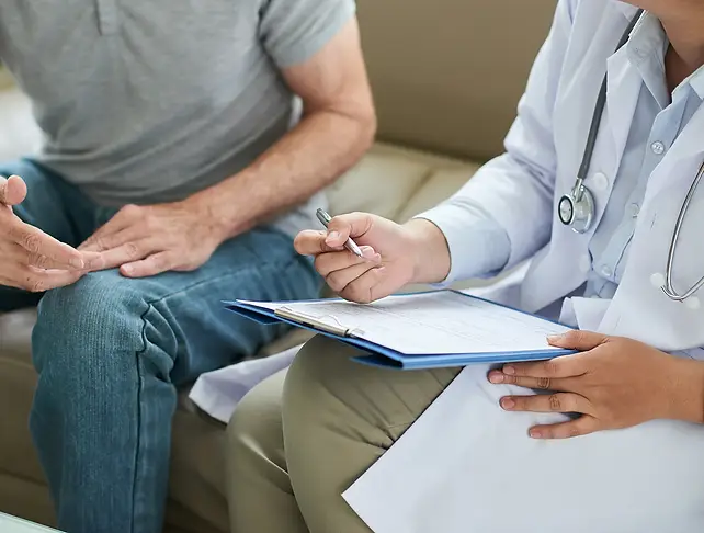 A male patient discusses his health with a doctor who is taking notes during a wellness consultation.